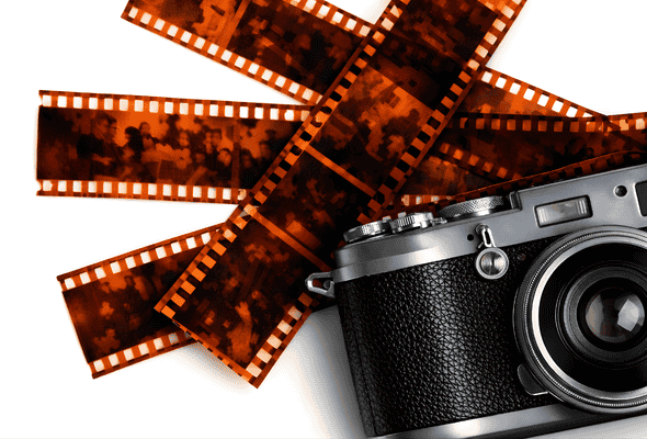 Vintage 35mm film camera with overlapping orange film negatives on a white background.